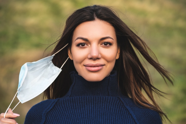 The young beautiful woman takes off the medical mask