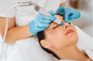 woman lying with her eyes closed while having a cleansing procedure on her face