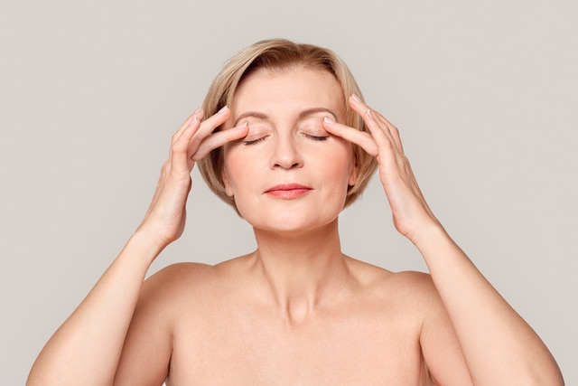 beauty concept close up applying eye cream on eyelids pensive