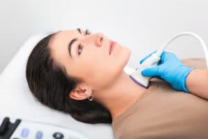 Woman patient receives thyroid diagnostics.