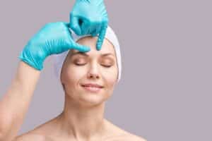 Surgeon evaluating a woman's brow before brow lift surgery